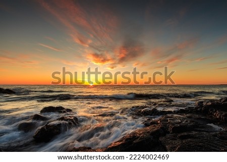Rocky shore of the Atlantic Ocean at high tide at sunset