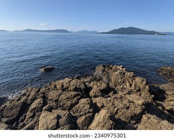 The rocky shore looking out upon the calm waters of the Puget Sound and islands in the distance.