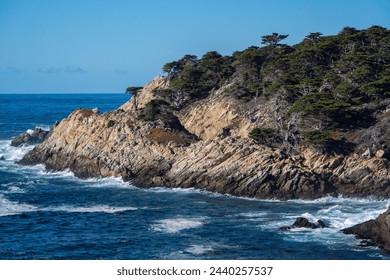 A rocky shoreline with a body of water in the background. The water is choppy and the rocks are jagged. The scene is serene and peaceful, with the trees providing a sense of calm - Powered by Shutterstock