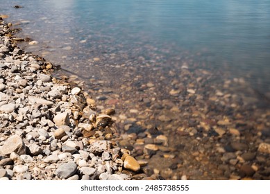 A rocky shoreline with a body of water in the background. The water is murky and the rocks are scattered throughout the area - Powered by Shutterstock