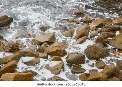 Rocky Shoreline With Crashing Waves Against Stones on a Cloudy Day at the Coast