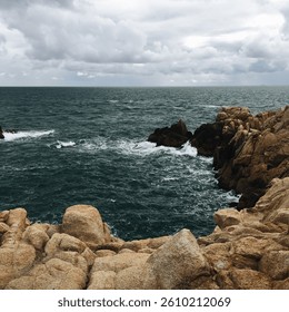 Rocky Shoreline with Crashing Waves Under a Moody Sky
