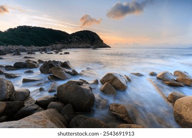 Rocky Shoreline at Sunset with Calm Waves and Scenic Hills, Shek O, Hong Kong - Powered by Shutterstock