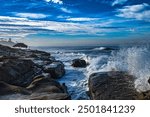 ROCKY SHORELINE AT THE WINDANSEA BEACH WITH A GRASS HUT AND WAVES CRASHING ON THE ROCKS SPRAYING WATER IN LA JOLLA CALIFORNIA NEAR SAN DIEGO