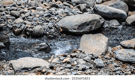 A rocky stream with a few rocks in it. The rocks are scattered throughout the stream, and the water is flowing between them. The scene is peaceful and serene, with the sound of the water - Powered by Shutterstock