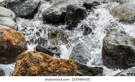 A rocky stream with water flowing over the rocks. The water is clear and the rocks are brown and gray - Powered by Shutterstock