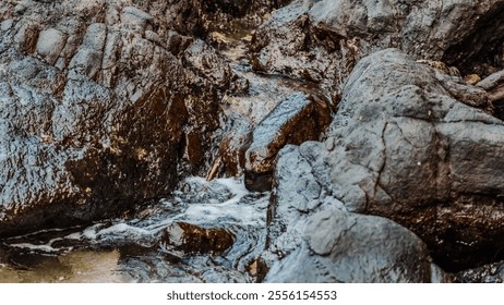 A rocky stream with water flowing through it. The water is murky and the rocks are large. The scene is peaceful and serene - Powered by Shutterstock