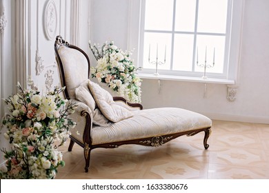 Rococo Style Sofa In A Bright Room Near A Vase Of Flowers And A Large Bright Window With Candlesticks