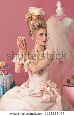 Rococo woman dressed as historical figure Marie Antoinette holding a piece of cake