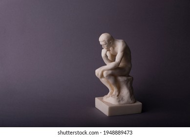 Rodin thinker statuette of the naked man on the grey background