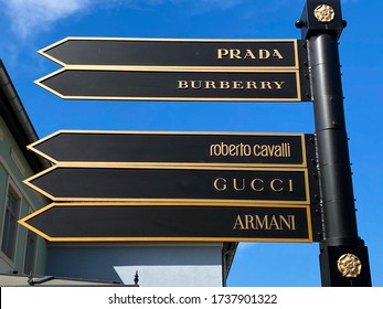 Roermond, Netherlands - May 19. 2020: View on direction arrows with luxury fashion brands against blue sky - textile industrie development concept