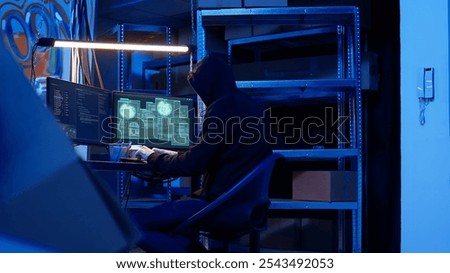 Rogue computer expert in graffiti sprayed hideaway targeting vulnerable unpatched connections, focused on getting past digital devices security and stealing valuable sensitive data, dolly in shot