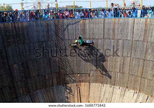 Rohtak, Haryana, India - 2 March,\
2020:unidentified indian circus biker riding a bike on the walls of\
a wooden well at a circus\
performance.