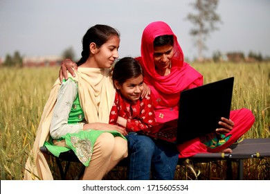 Rohtak, Haryana, India - March 16, 2016: Rural family using laptop outdoor in nature.