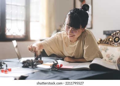 Role Playing Tabletop And Board Game Hobby Concept. Happy Young Adult Asian Woman Enjoying With Storytelling Fantasy Adventure. Blur Foreground With Monster Miniatures And Dice Component.