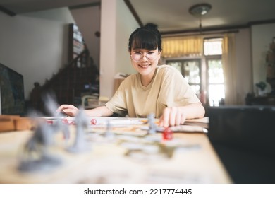 Role Playing Tabletop And Board Game Hobby Concept. Happy Young Adult Asian Woman Enjoying With Storytelling Fantasy Adventure. Blur Foreground With Monster Miniatures And Dice Component.