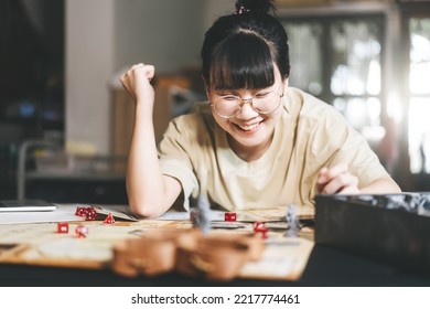 Role Playing Tabletop And Board Game Hobby Concept. Happy Young Adult Asian Woman Enjoying With Storytelling Fantasy Adventure. Blur Foreground With Monster Miniatures And Dice Component.