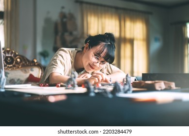 Role Playing Tabletop And Board Games Hobby Concept. Young Adult Asian Woman Enjoying With Storytelling. Blur Foreground With Monster Miniatures And Dice Component.