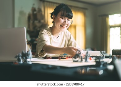 Role Playing Tabletop And Board Games Hobby Concept. Young Adult Asian Woman Using Laptop For Streaming Online With Friends. On Table With Blur Dice And Miniatures.