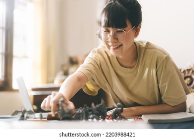 Role Playing Tabletop And Board Games Hobby Concept. Young Adult Asian Woman Enjoying With Storytelling. Blur Foreground With Monster Miniatures And Dice Component.