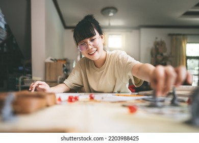 Role Playing Tabletop And Board Games Hobby Concept. Young Adult Asian Woman Enjoying With Storytelling. Blur Foreground With Monster Miniatures And Dice Component.