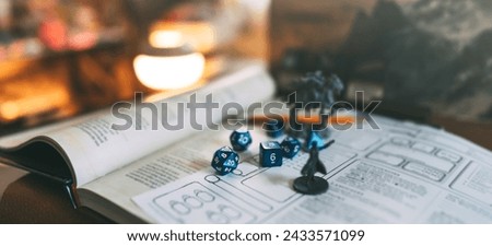 Role playing tabletop game and board games hobby concept. Miniatures and blue dice place on adventure story TTRPG book and character sheets. No people background.