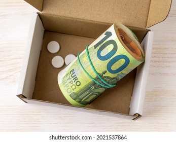 Roll Of 100 Euro Banknotes And Few Pills In An Open Small Cardboard Box. Saving Money For Health Care And Treatment, Planning For Expenses Concept. Keep Wad Of Money At Home. Top View. 