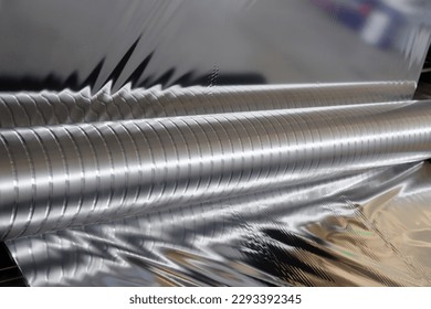 Roll of aluminum foil for food packaging on the automatic packing machine in food product factory. - Shutterstock ID 2293392345
