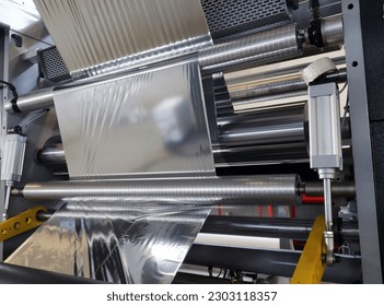Roll of aluminum foil for food packaging on the automatic packing machine in food product factory. - Shutterstock ID 2303118357