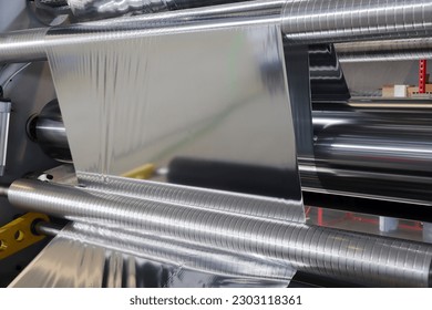 Roll of aluminum foil for food packaging on the automatic packing machine in food product factory. - Shutterstock ID 2303118361