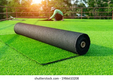 Roll Of Astroturf Or Field Turf Matting Of Artificial Grass Soccer Field,green Lawn Background With Workers Pave The Counterfeit Grass With Sunlight Background.