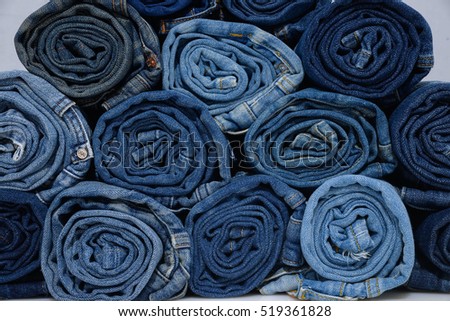 roll blue denim jeans arranged in stack-gray background 