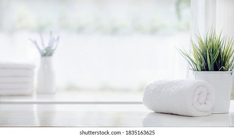 Roll Of Clean Bath Towel And Houseplant On White Table, Copy Space.