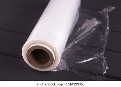 Roll Of Cling Film On A Black Wooden Table.