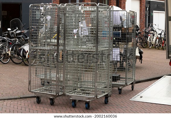 Roll containers or roll cage trolleys  on\
the road unloaded from a truck with open\
flap.
