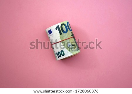 Roll of  euro money. 100 euro banknote with red rubber band. Moneyfinance at pink background 