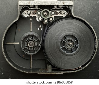 A Roll Of Film In A Film Camera Cassette. Negative Film In The Tape Drive Mechanism Of The Cassette. Show Business Film Production Technology Concept