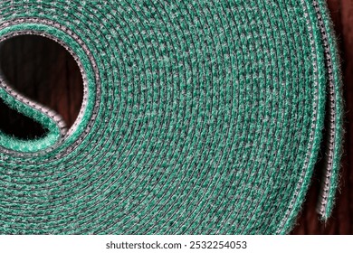Roll of green nylon hook and loop fastener or velcro tape for garden or home, close up. Velcro tape is used in the garden to support plants to sticks