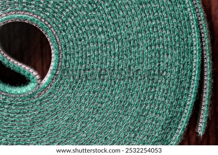 Roll of green nylon hook and loop fastener or velcro tape for garden or home, close up. Velcro tape is used in the garden to support plants to sticks