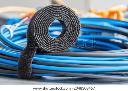 Roll of hook and loop, velcro tape with bundle of cables, electrical installations accessories and telecommunication