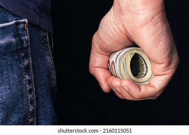 Roll of hundred us dollars in male fist. Banknotes rolled up in man hand closeup on black background - Shutterstock ID 2160115051