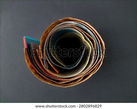 Roll of Indonesian currency notes viewed from above forming a swirl pattern that symbolizes cash flow and financial accumulation.