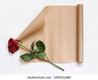 A Roll Of Kraft Paper And A Faded Red Rose Flower, A Concept Of The Past And Old Letters.