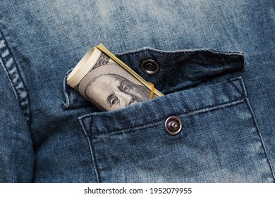 A Roll Of One Hundred Dollar Bills Sticks Out Of A Denim Shirt Pocket. Close Up.