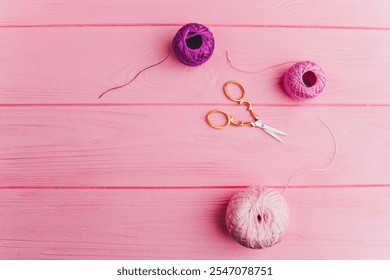 A roll of pink and purple skeins of thread and iron scissors lie on a wooden pink surface, perfect for decorating, gift wrapping and sewing. - Powered by Shutterstock