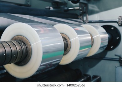 Roll Of Plastic Packaging Film On The Automatic Packing Machine In Food Product Factory. Industrial And Technology Concept. Vintage Photo And Film Style.