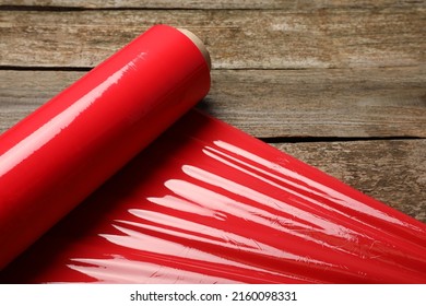 Roll of red plastic stretch wrap on wooden background, closeup - Shutterstock ID 2160098331