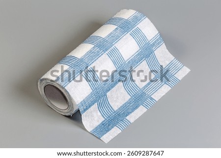 Roll of the reusable blue checkered kitchen towels with tear-off sheets on a gray surface
