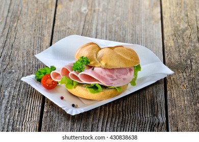 Roll With Sliced Ham Sausage On A Paper Plate With A Napkin