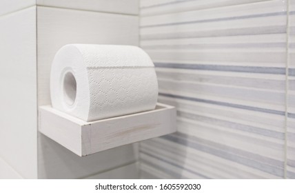 Roll of toilet paper on the background wall in the restroom. White gray.
